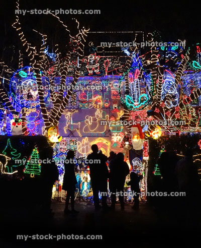 Stock image of people looking at house with colourful Christmas lights at night