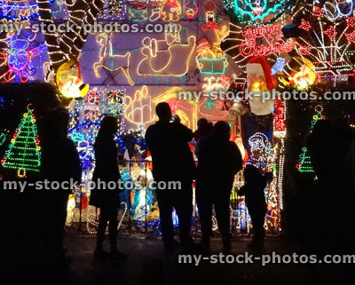 Stock image of people looking at house with colourful Christmas lights at night