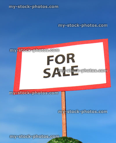 Stock image of small toy model house For Sale / Sold sign, blue sky