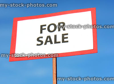 Stock image of small toy model house For Sale / Sold sign, blue sky