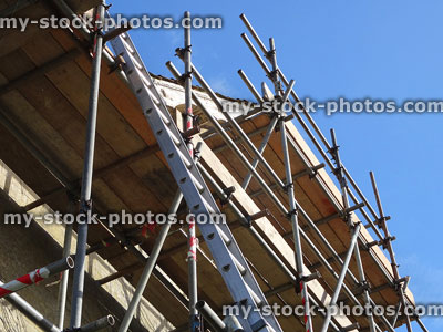 Stock image of house with builder's scaffolding poles / staging outside, ladder