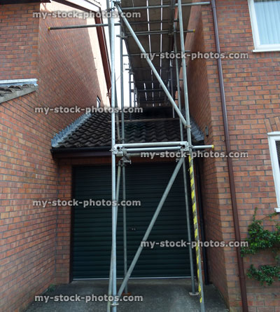 Stock image of scaffolding tower on garage roof, link detached house, fascia boards