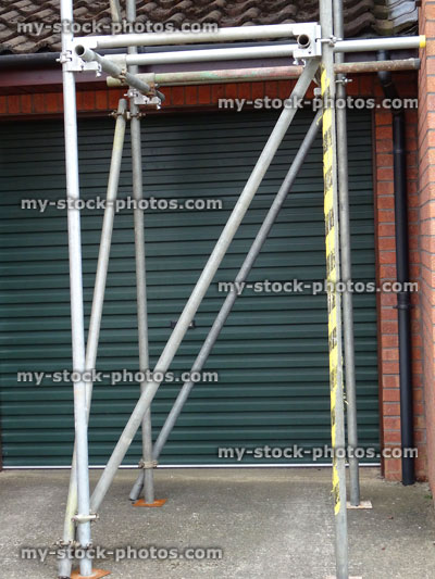 Stock image of scaffolding tower on concrete driveway, by garage door