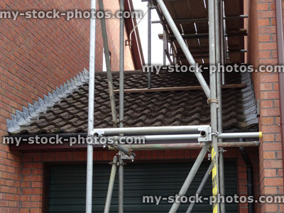 Stock image of scaffolding poles on garage roof tiles, wooden base