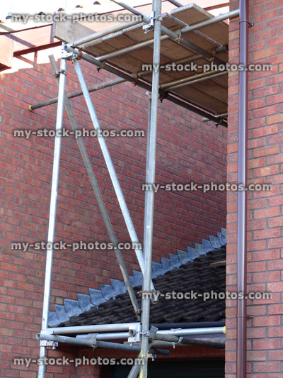 Stock image of scaffolding tower on side of red brick house, construction work