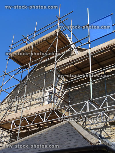 Stock image of scaffolding tower against stone cottage wall and roof