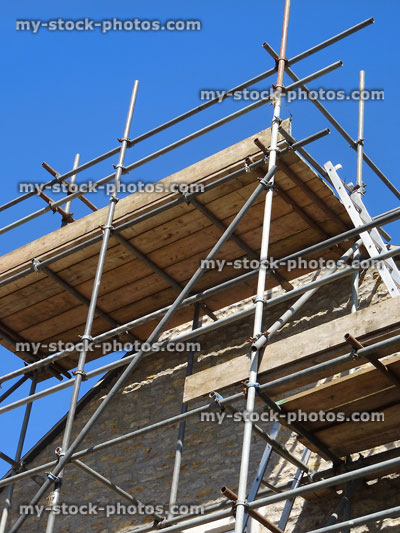 Stock image of wooden scaffolding platform with planks, cobblestone house wall