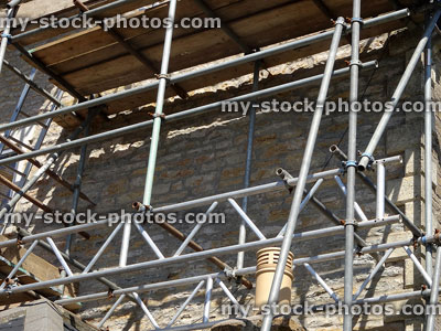 Stock image of cobblestone house wall repairs using metal scaffolding tower