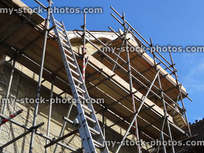 Stock image of house, rotting fascia boards, scaffolding poles / planks, extending ladder