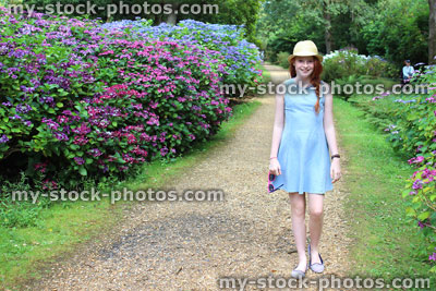 Stock image of girl walking past hydrangea flowers, woodland walk / gravel path
