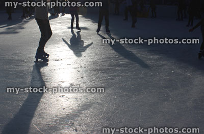 Stock image of sunny outdoor ice skating rink with skaters / shadows