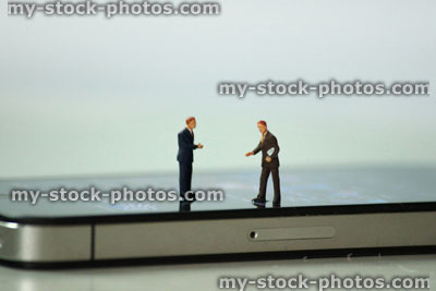 Stock image of mini businessmen having a meeting on iPhone screen