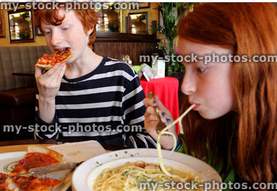 Stock image of boy and girl eating spaghetti and pizza in Italian restaurant