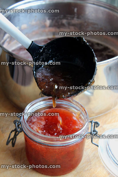 Stock image of hot strawberry jam being ladled into sterilised glass jam jars