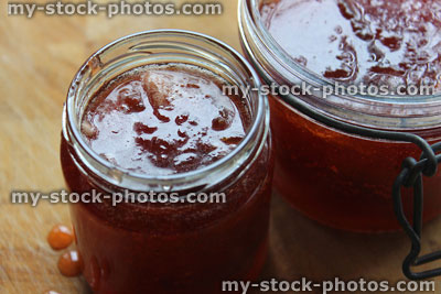 Stock image of homemade plum and strawberry jam, glass jam jars, lever arm clip