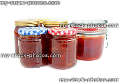 Stock image of homemade plum and strawberry jam in glass jars, metal clip, screw lids