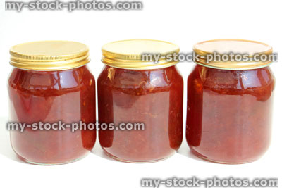 Stock image of homemade plum and strawberry jam in glass jars, screw lids
