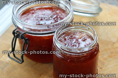 Stock image of homemade plum and strawberry jam, glass jam jars, lever arm clip