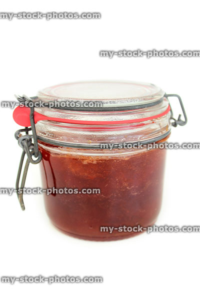 Stock image of homemade plum and strawberry jam in glass jar, metal clip