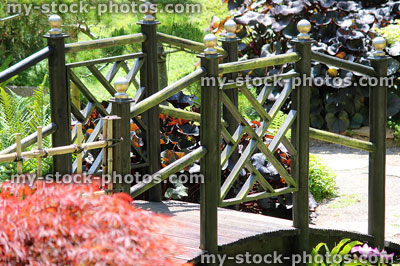 Stock image of black wooden Japanese bridge in garden with maples