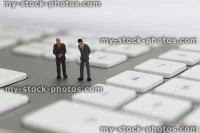 Stock image of businessmen figurines stood on ultra thin anodised aluminium computer keyboard