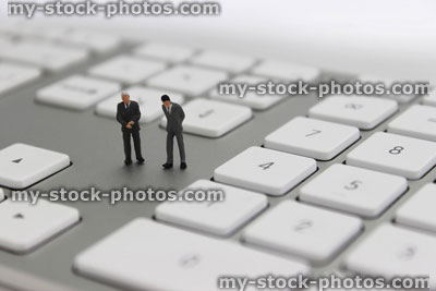 Stock image of businessmen figurines stood on ultra thin anodised aluminium computer keyboard