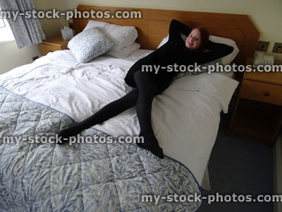 Stock image of teenage girl lying on king size double bed with quilt cover