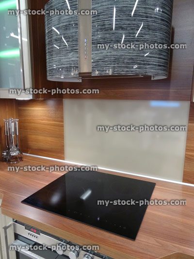 Stock image of modern kitchen, touch built in ceramic hob cooker, glass cabinets, wooden worktop, lighting