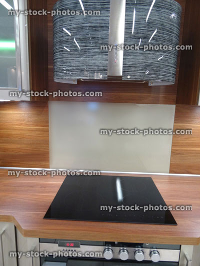 Stock image of modern kitchen, touch built in ceramic hob cooker, glass cabinets, wooden worktop, splashback