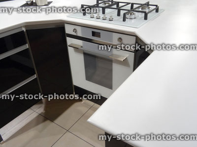 Stock image of modern monochrome, black / white kitchen, gas hob, electric oven, corian worktop counter, island