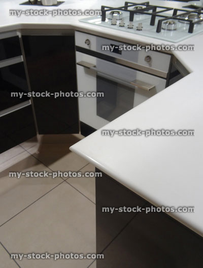 Stock image of modern monochrome, black / white kitchen, gas hob, electric oven, corian worktop counter, island