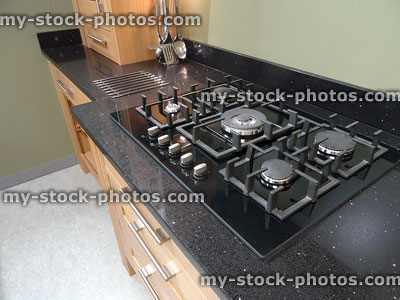 Stock image of gas cooker hob in kitchen, sparkly black granite worktop