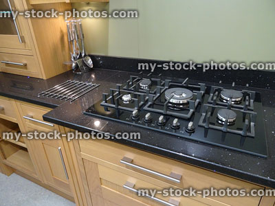 Stock image of five-ring gas cooker hob in beechwood kitchen, granite-countertop