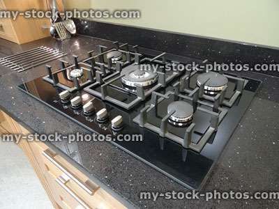 Stock image of modern kitchen with black granite worktop, gas-hob cooker
