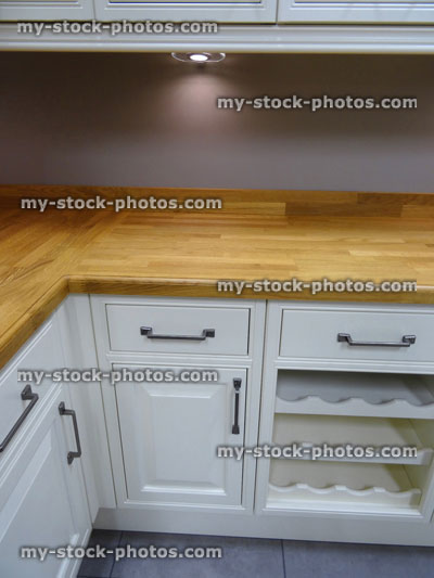 Stock image of kitchen corner, real wood worktop counters, white painted cabinets cupboards, wine rack