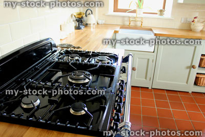 Stock image of traditional country kitchen, range cooker with gas rings, wooden worktops