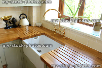 Stock image of traditional country kitchen, white Belfast ceramic sink with wooden worktops