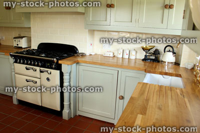 Stock image of traditional country kitchen, gas range cooker, Belfast / butler ceramic sink, pale green cabinets