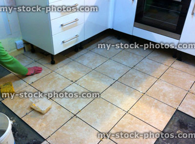 Stock image of kitchen floor being tiled, square stone travertine tiles