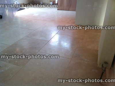 Stock image of kitchen floor being tiled, rectangular stone travertine tiles