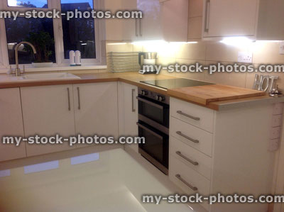 Stock image of contemporary white kitchen, glossy white cupboards, drawers, cooker
