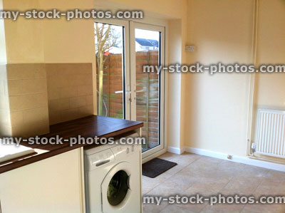 Stock image of modern kitchen diner, white cupboards, washing machine, patio doors / back garden