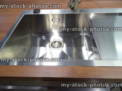 Stock image of stainless steel kitchen sink / single basin, real walnut dark wood worktop counter top