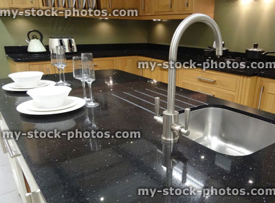 Stock image of traditional kitchen, black granite worktop counter island, stainless steel sink, wooden cupboards cabinets