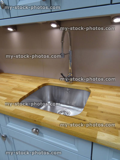 Stock image of stainless steel kitchen sink / single basin, real oak wood worktop counter top