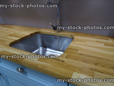 Stock image of stainless steel kitchen sink / single basin, real oak wood worktop counter top
