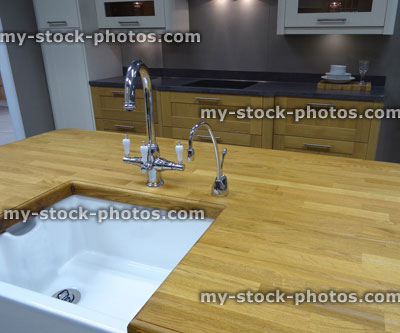 Stock image of traditional kitchen, wooden worktop counter, white ceramic Belfast / Butler sink, island