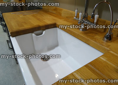 Stock image of white ceramic Belfast butler sink, wooden kitchen worktop