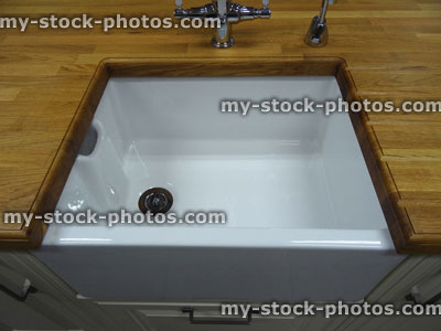 Stock image of traditional kitchen, wooden worktop counter, white ceramic Belfast / Butler sink