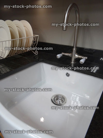 Stock image of traditional kitchen, black granite worktop counter, white ceramic Belfast / Butler sink